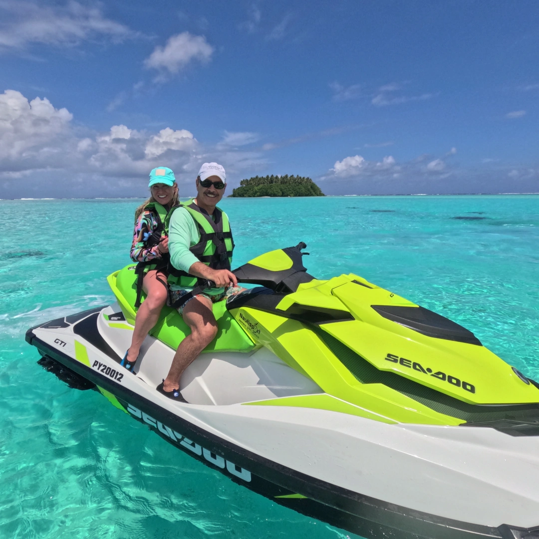 Couple souriant sur un jet ski Sea-Doo vert et blanc devant un motu paradisiaque à Raiatea. Couple, petit îlot au fond